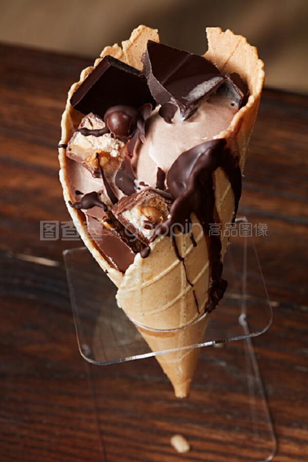 在木制的深色背景上,放着融化的冰淇淋、巧克力糖浆和巧克力片